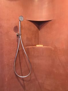 a shower head and hand held showerhead in a bathroom with copper colored wallpaper