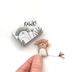 a tiny toy is being held up by someone's hand with the word raw on it