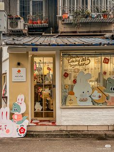 a store front with an assortment of cartoon characters on the window and in front there is a sign that says lucky cat kitchen