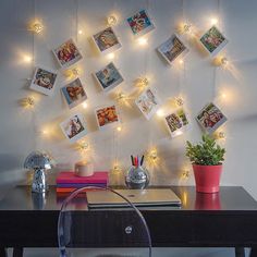 a desk with a chair and some pictures on the wall above it that have lights strung from them