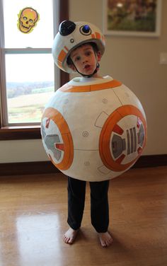 a young boy wearing a star wars bbg helmet and standing in front of a window