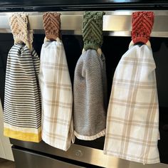 three kitchen towels hanging on the oven door handle with knoted ends and ties attached to them