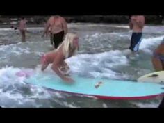 people are standing in the water with surfboards and one person is on a surfboard