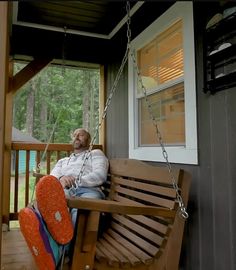 a man sitting on a porch swing with an orange frisbee next to him