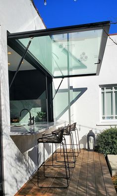 an outdoor kitchen and dining area on a wooden deck with glass doors to the outside