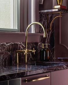 two faucets on a marble counter top next to a window