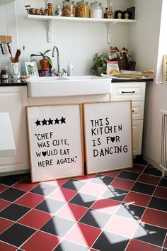 two framed posters sitting on the floor in a kitchen