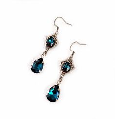 These dainty and elegantly ornate earrings are made with antique silver plated centerpieces, and silver tone settings, worn with stainless steel earring hooks. They are accented with dazzling dark aqua/teal glass crystals/jewels. Earrings measure 2 1/8" in length (including earring hooks) and 1/2" wide. More colors are available in our shop, along with matching chokers.If you don't see items with a color you want, feel free to ask about availability.