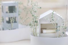 a house shaped planter sitting on top of a table next to a white vase