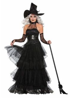 a woman in a black dress and hat with a broom on her head is posing for the camera