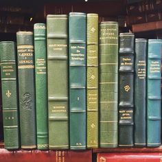 many books are stacked on top of each other in a row and one is green