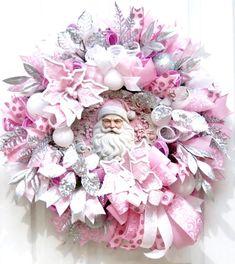 a pink wreath with a santa claus face and lots of silver decorations on it's front door