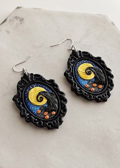 the earrings are decorated with black and yellow designs