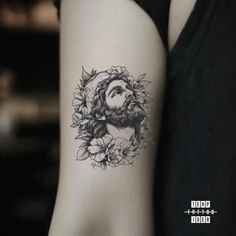 a woman's arm with a tattoo of jesus and flowers on the left side