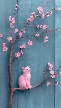 a pink cat sitting on top of a tree branch next to a blue wooden wall