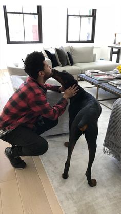 a man kneeling down next to a black dog