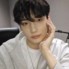 a young man sitting in front of a microphone with his hand on his ear and looking at the camera