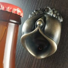 a close up of a metal bell on a wall next to a glass bottle with liquid in it