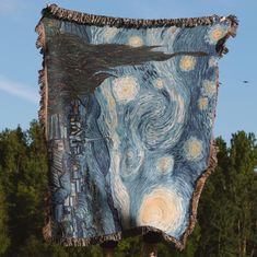 a person holding up a blanket with an image of the starry night