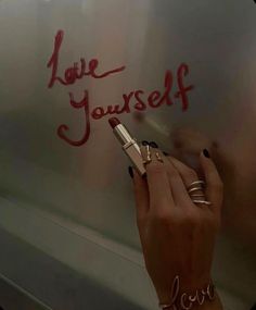 a woman writing on the side of a whiteboard that says love youself