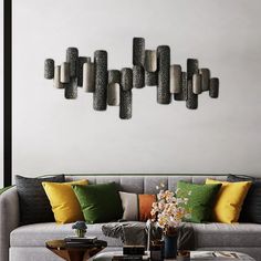 a living room filled with lots of furniture next to a wall mounted art piece on the wall