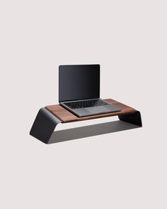 a laptop computer sitting on top of a wooden desk with a black keyboard and mouse pad