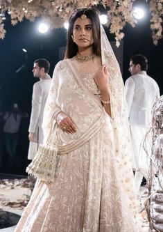 a woman in a wedding dress standing under a chandelier