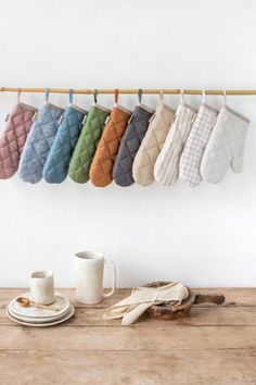 several oven mitts hanging on a rack next to a coffee cup and saucer