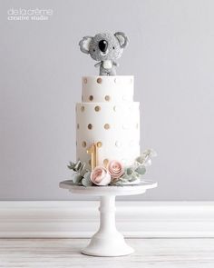 a white cake with gold polka dots and a koala on top