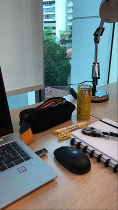 an open laptop computer sitting on top of a wooden desk next to a notebook and pencils