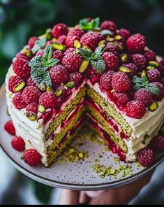 a cake with raspberries and pistachios on top