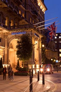 the london hotel is lit up at night and people are walking on the sidewalk outside