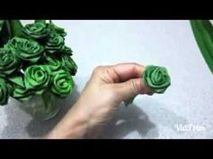 someone is holding some green flowers in their hand and it looks like they are made out of paper