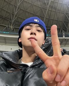 a young man making the peace sign with his hand in front of him at an indoor arena