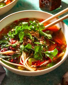 a bowl of soup with chopsticks on the side and another bowl in the background