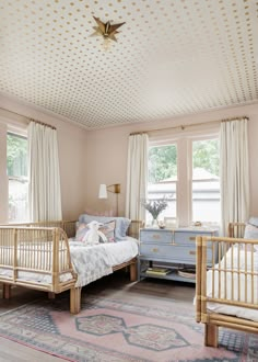 a baby's room with two cribs and a rug on the floor