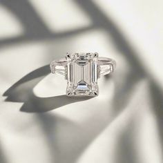 an emerald - cut diamond ring with baguets is shown on a white background