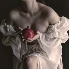 a shirtless man holding an apple in his hands and wearing a white dress with ruffles