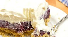 a piece of cake with white frosting and blueberries on it is sitting on a plate