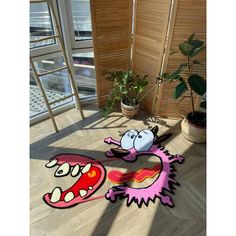 a cartoon character rug on the floor next to a potted plant and window sill