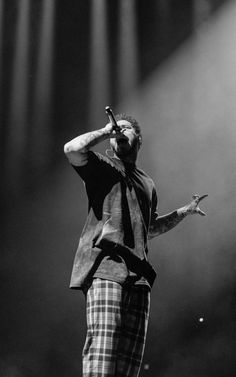 a man standing on top of a stage with his hands in the air while holding a microphone