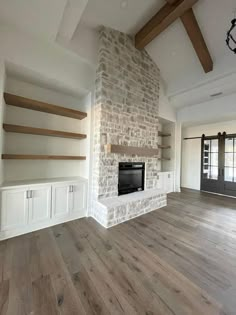 an empty living room with wood flooring and brick fireplace