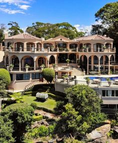 an aerial view of a large mansion with pool and landscaping in the foreground, surrounded by trees