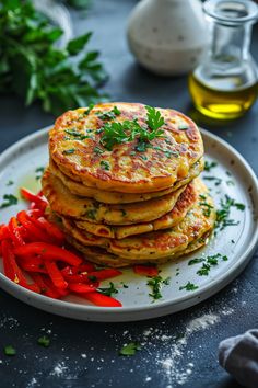 a stack of pancakes sitting on top of a white plate next to red peppers and parsley