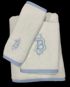 three white towels with blue trims and monogrammed letters on the bottom one