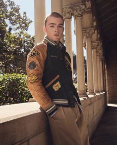 a man in uniform leaning against a wall with his hands on his hips and looking at the camera