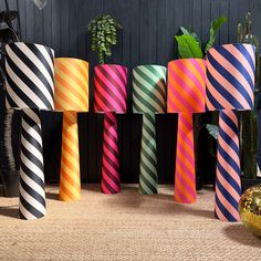 several different colored striped vases sitting next to each other on the floor in front of a black wall