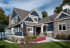 a large house with blue siding and white trim on the windows, along with landscaping