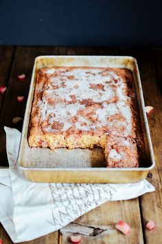 a cake in a pan with powdered sugar on top and rose petals around it