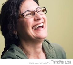 a woman wearing glasses and smiling with her mouth wide open in front of the camera